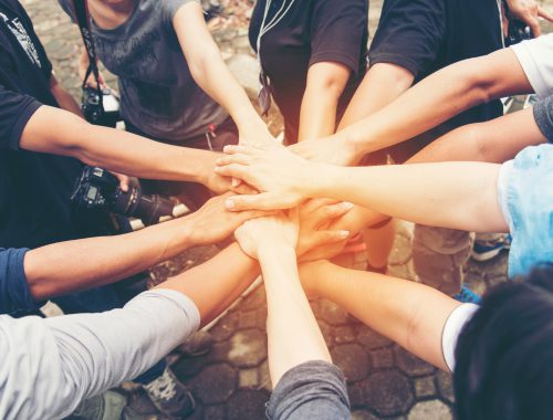 Photo of teens joining hands in a circle.